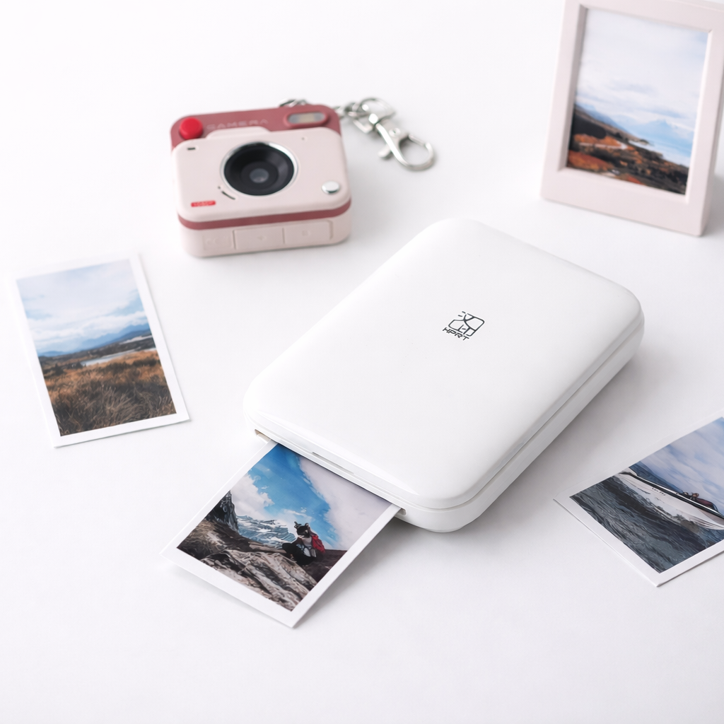 White portable photo printer with instant photos on a white surface